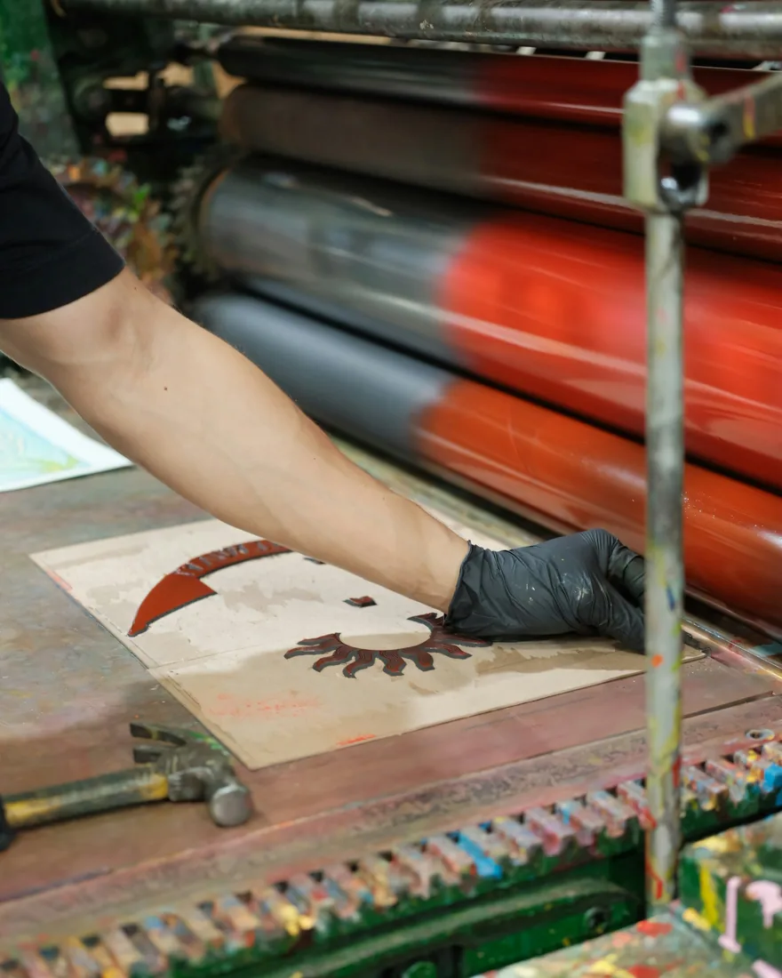 Manos con guante aplicando tinta sobre una plancha de grabado durante el proceso de entintado